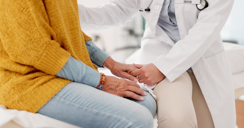 A doctor carefully examines the hand of an elderly woman at heroin rehab center