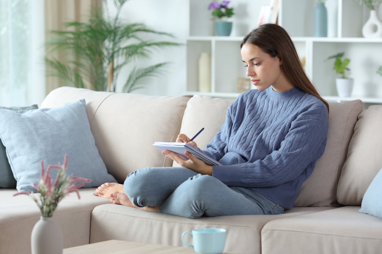 Woman writing notes at home as she prepares for a difficult conversation about a loved one’s addiction.
